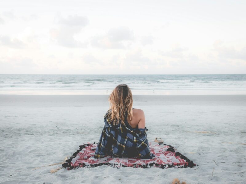 woman sitting on blanket located on shoreline