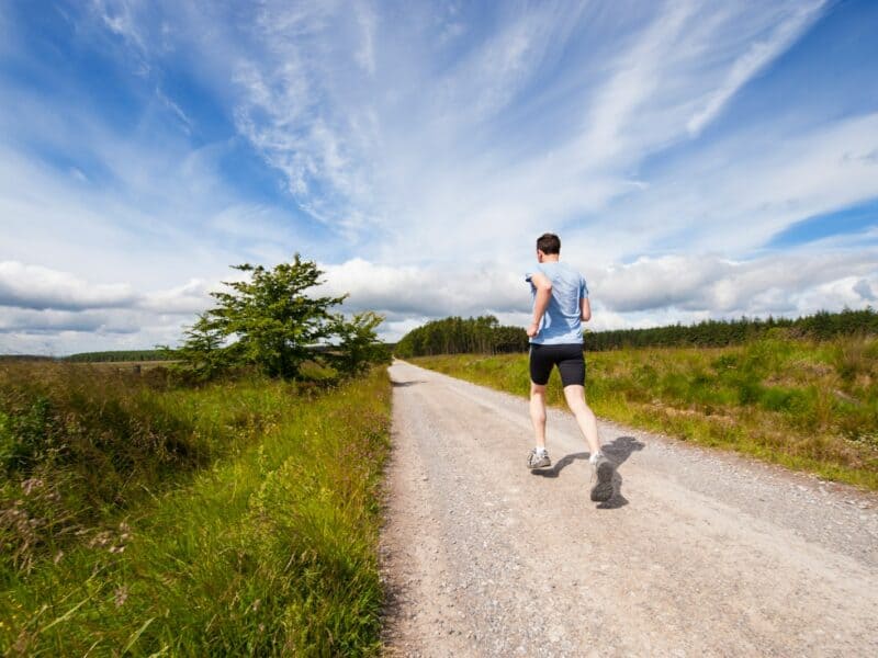 man running on road near grass field