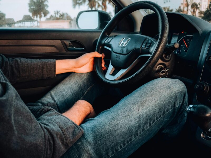 person holding black Honda car steering wheel
