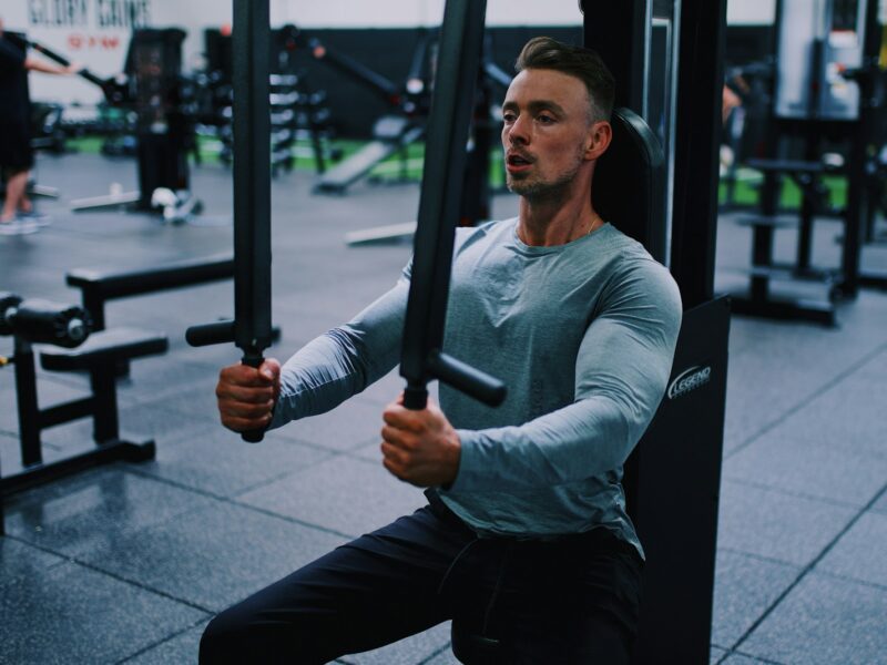 man in gray long sleeve shirt and black pants holding black metal bar