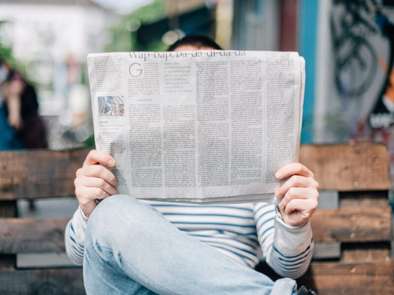 man sitting on bench reading newspaper